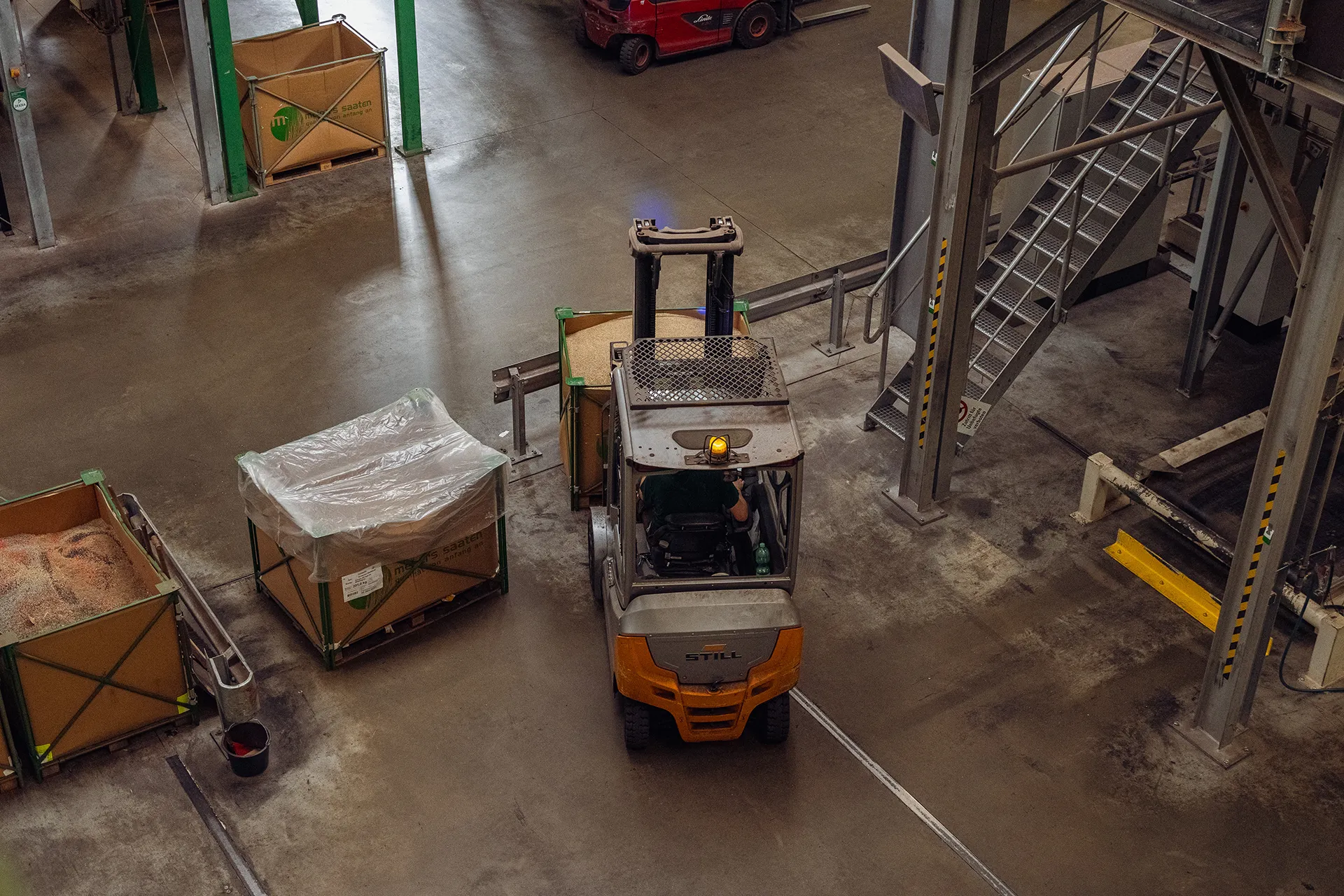 Gabelstapler transportiert Saatgut in Industriehalle, effiziente Logistik und Lagertechnik für Getreideproduktion.